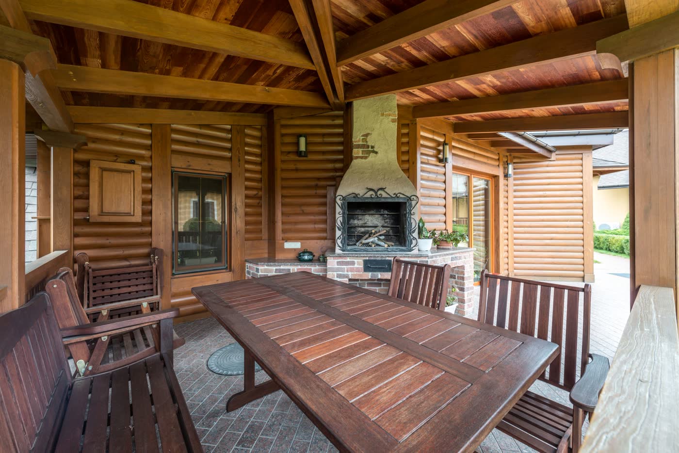 Galería exterior con mesa de madera y hogar bajo techo